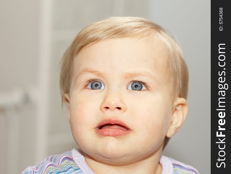 Baby with clear blue eyes and fair skin look up with perplex expression