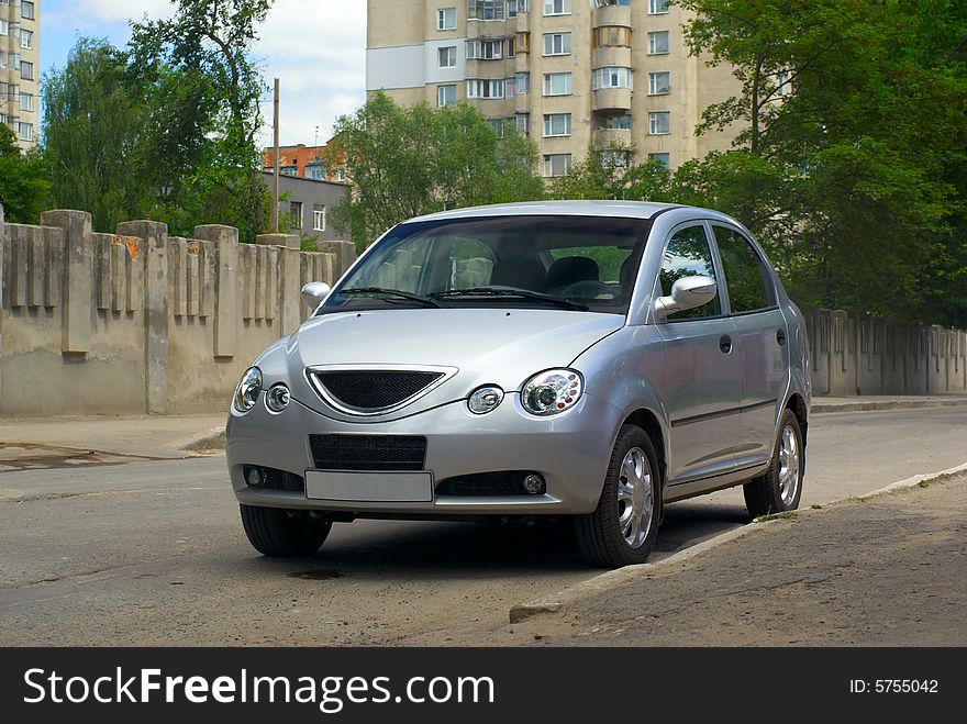 Silvery car stand at road near fence