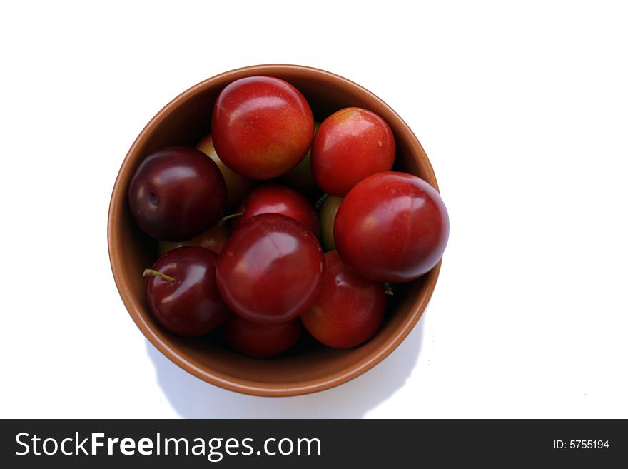 Plums in brown bowl isolated on white bacground
