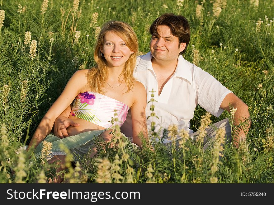 Happy couple sitting in the grass enjoying being together