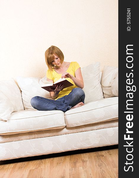 A young beautiful woman is reading on a lounge