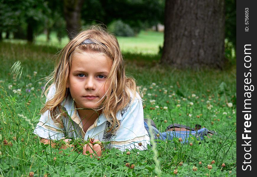 Boy with long blond hair is lying in the grass. Boy with long blond hair is lying in the grass