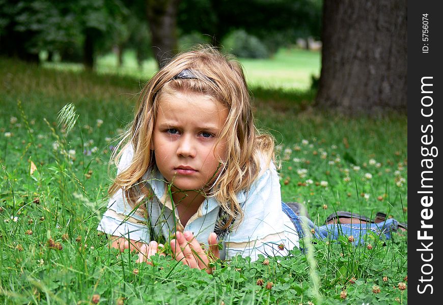 Boy with long blond hair is lying in the grass. Boy with long blond hair is lying in the grass