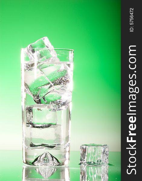 Tall iced drink on fresh green gradient lighting with melting ice cube. Tall iced drink on fresh green gradient lighting with melting ice cube