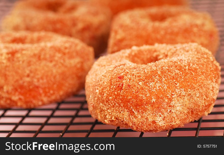 Freshly made strawberry doughnuts with a sugar coating cooling on a wire rack. Freshly made strawberry doughnuts with a sugar coating cooling on a wire rack