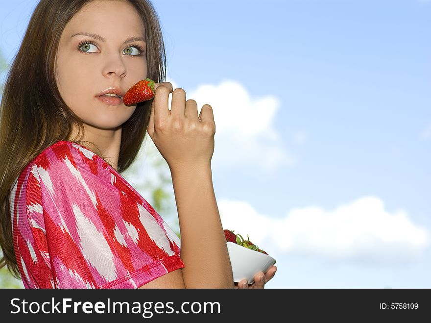 Pretty girl relaxing on green grass and eat red fr