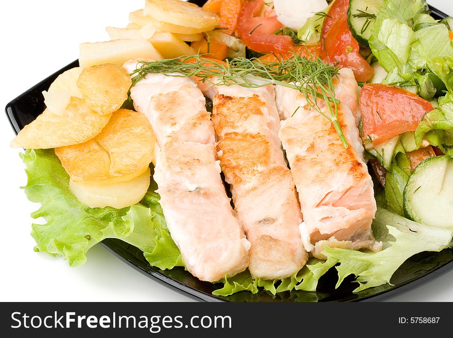 Stake from a salmon with vegetables on a plate. Closeup.