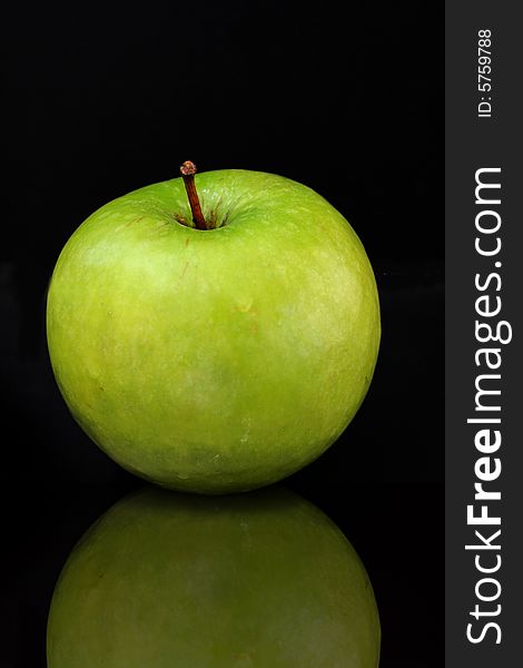 Green apple isolated on a black bacground with a reflection.