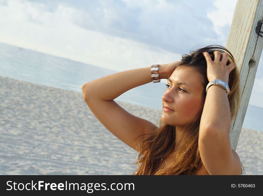 Woman at the beach lifting her hair and watching the water.