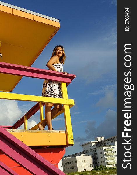 Woman atop a lifeguard hut glancing over her shoulder. Woman atop a lifeguard hut glancing over her shoulder.