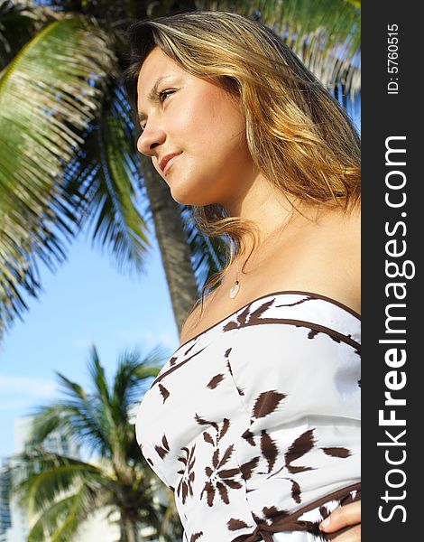 Woman glancing to the side with a palm on a blue sky in the background. Woman glancing to the side with a palm on a blue sky in the background.