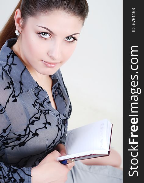 Beautiful young girl in a grey business suit with a diary and writing pen in hands. Beautiful young girl in a grey business suit with a diary and writing pen in hands