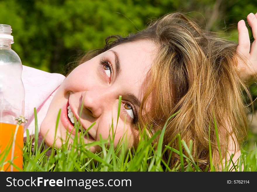 Pretty woman drinking juice on the summer glade