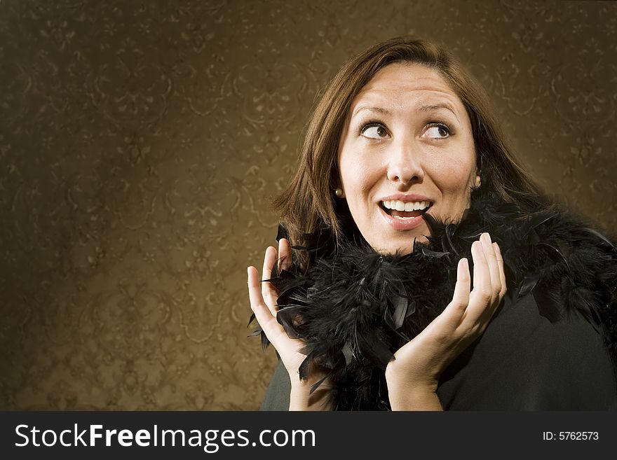 Pretty Hispanic Woman Wearing a Feather Boa in front of Gold Wallpaper. Pretty Hispanic Woman Wearing a Feather Boa in front of Gold Wallpaper