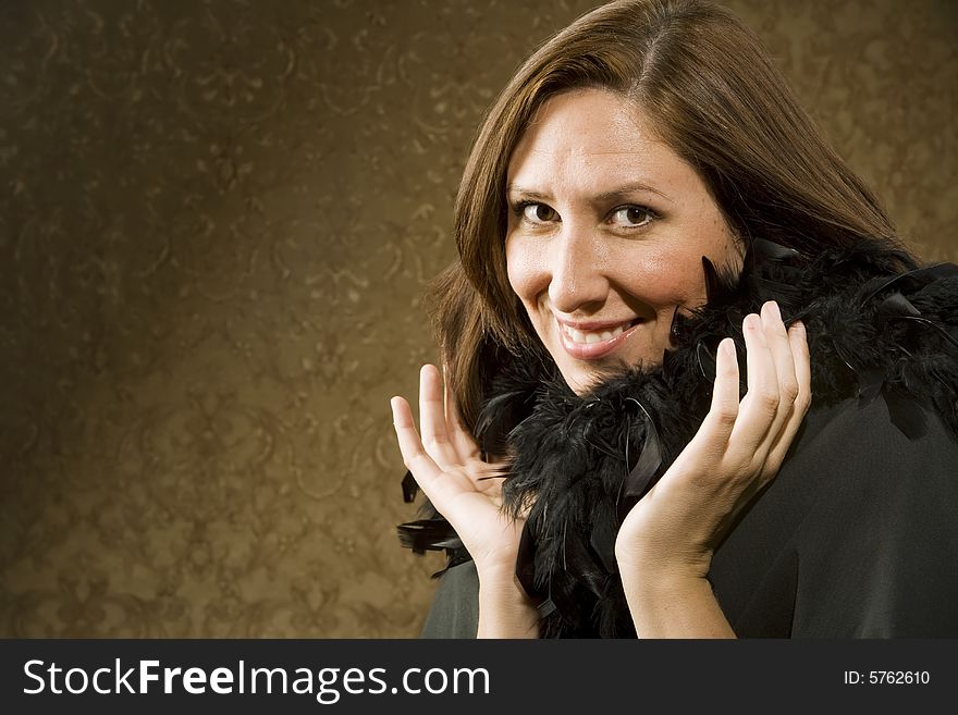 Pretty Hispanic Woman Wearing a Feather Boa in front of Gold Wallpaper. Pretty Hispanic Woman Wearing a Feather Boa in front of Gold Wallpaper