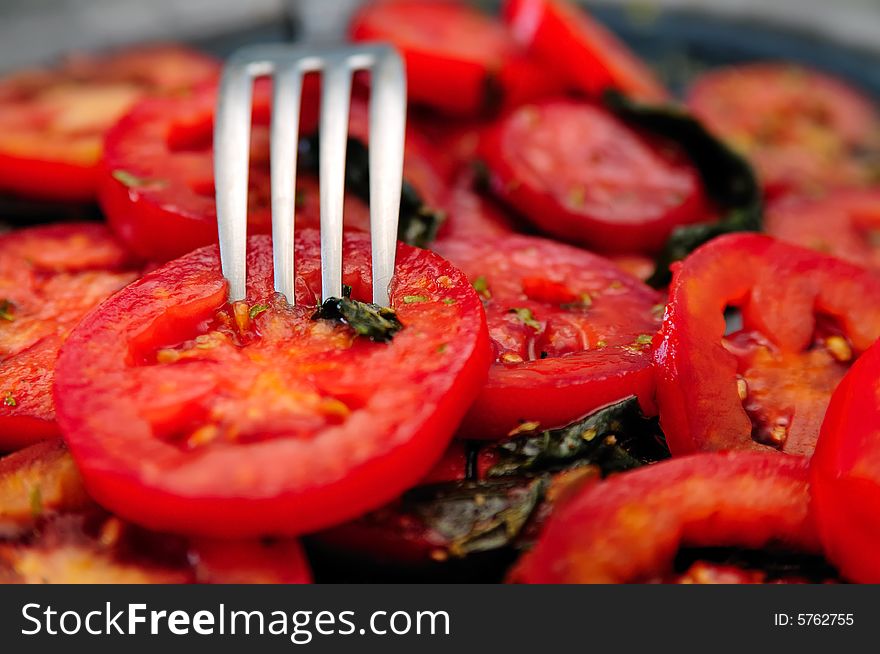 Tomato slices salad with basil and some other spices, all with a fork in. Tomato slices salad with basil and some other spices, all with a fork in.