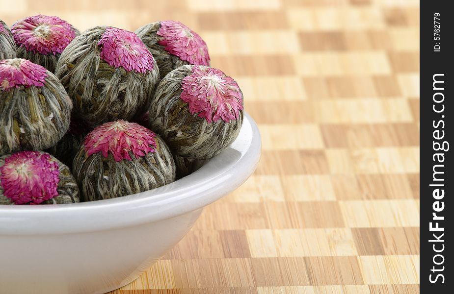 Several hand sewn balls of flowering tea in a white bowl. Several hand sewn balls of flowering tea in a white bowl.