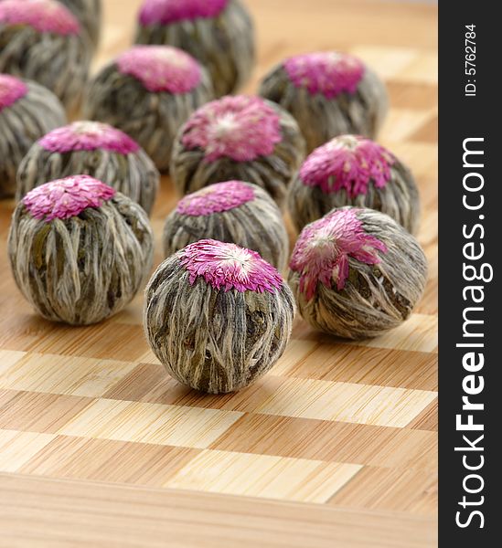 Several handsewn balls of flowering tea ion a bamboo counter. Several handsewn balls of flowering tea ion a bamboo counter.