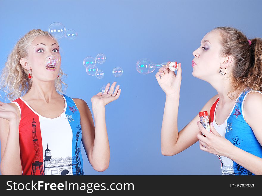 Two beautiful girls dressed in identical shirts play, inflating soap-bubbles. Two beautiful girls dressed in identical shirts play, inflating soap-bubbles