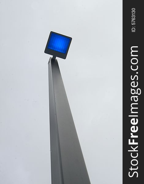 Bright blue light from light pole on grey day