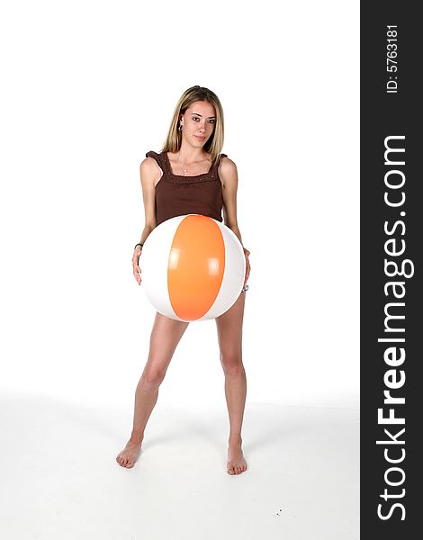 Teenage girl holding beach ball in front of her body; over high key