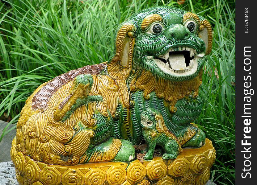 Close-up of pottery lion or dog in deep grass in garden. Close-up of pottery lion or dog in deep grass in garden