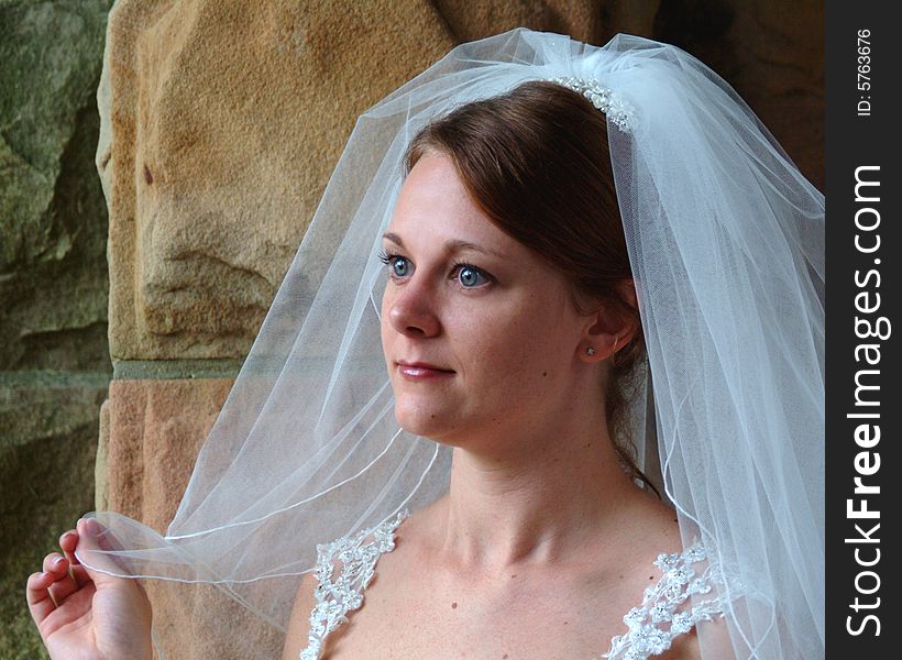 Closeup of bride looking out of stone window. Closeup of bride looking out of stone window