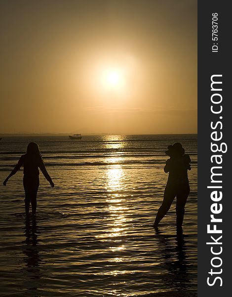 A silhouette of two people in the water. A silhouette of two people in the water