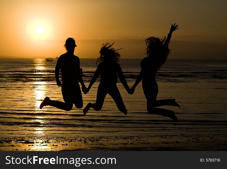 A silhouette of girls jumping in water.