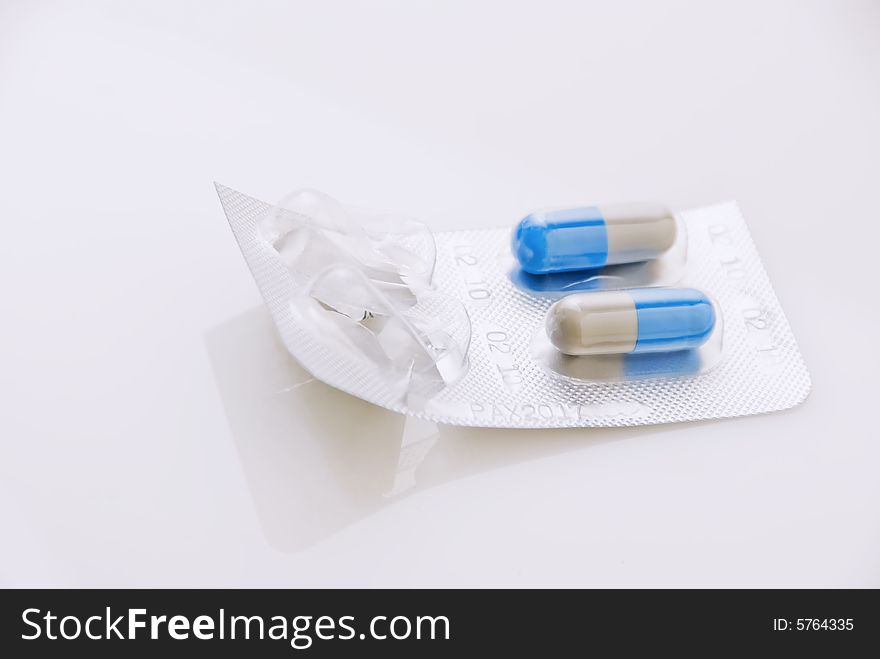 Blue capsules inside blister pack, on white background