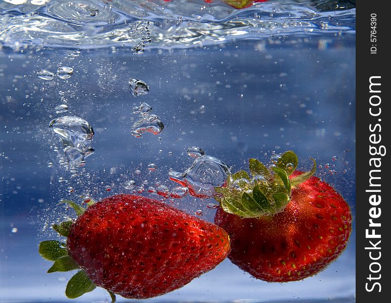 Pair of strawberries splashing into water. Pair of strawberries splashing into water
