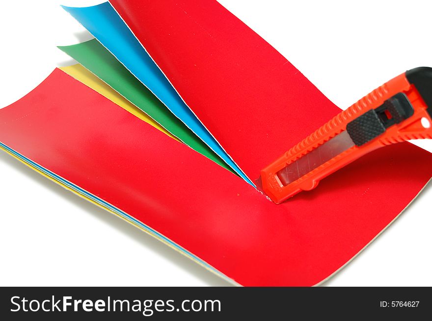 The knife cuts a color paper isolated on a white background. The knife cuts a color paper isolated on a white background