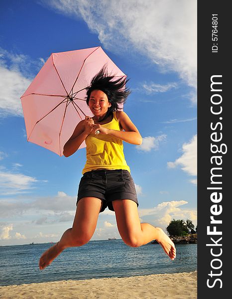 Jumping, smiling girl on the beach with an umbrella. Jumping, smiling girl on the beach with an umbrella.