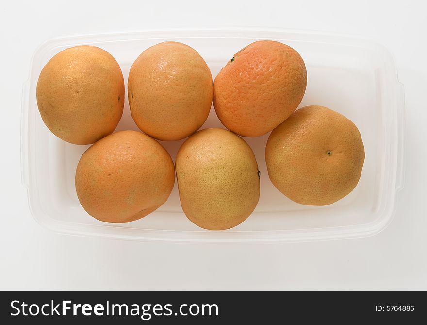 Six pieces of orange fruit in plastic container. Six pieces of orange fruit in plastic container