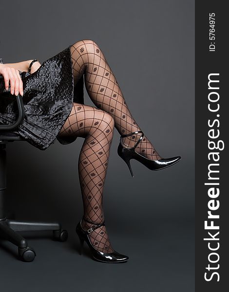 Beautiful female legs in black stockings on a dark background
