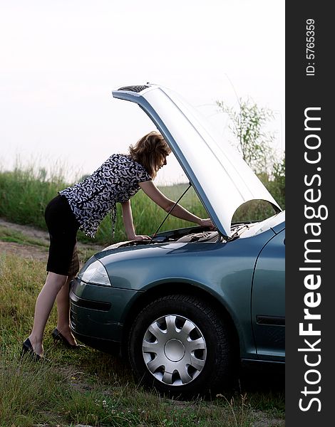 A beautiful girl trying to repair the car