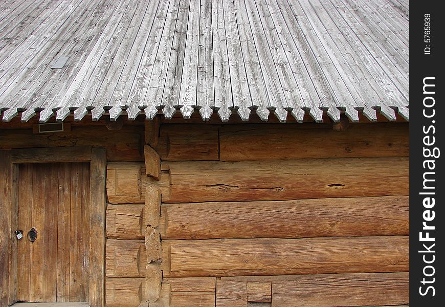 Greater rural log hut from round brown logs, with a roof and a door