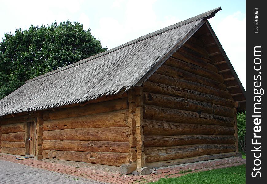 Greater rural log hut from round brown logs, with a roof and a door