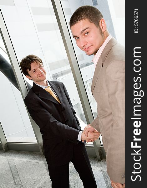 Two young businessmen greet each other by shaking hands. Two young businessmen greet each other by shaking hands