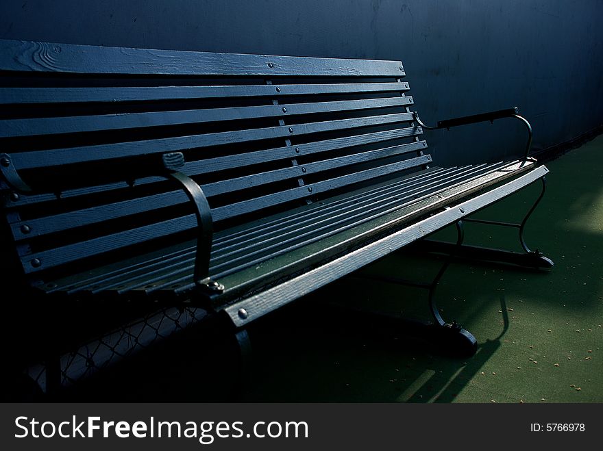 Classic dark green bench on a tennis court. Classic dark green bench on a tennis court