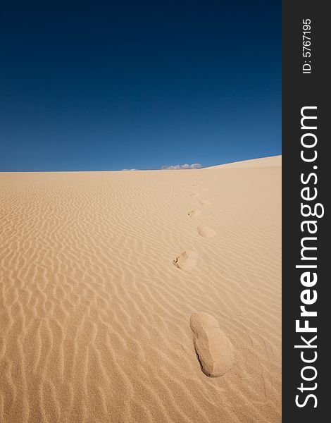 Footsteps in the dunes under a blue sky. Footsteps in the dunes under a blue sky.