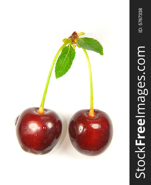 Pair of cherries with fruit stem and green leafs isolated on white