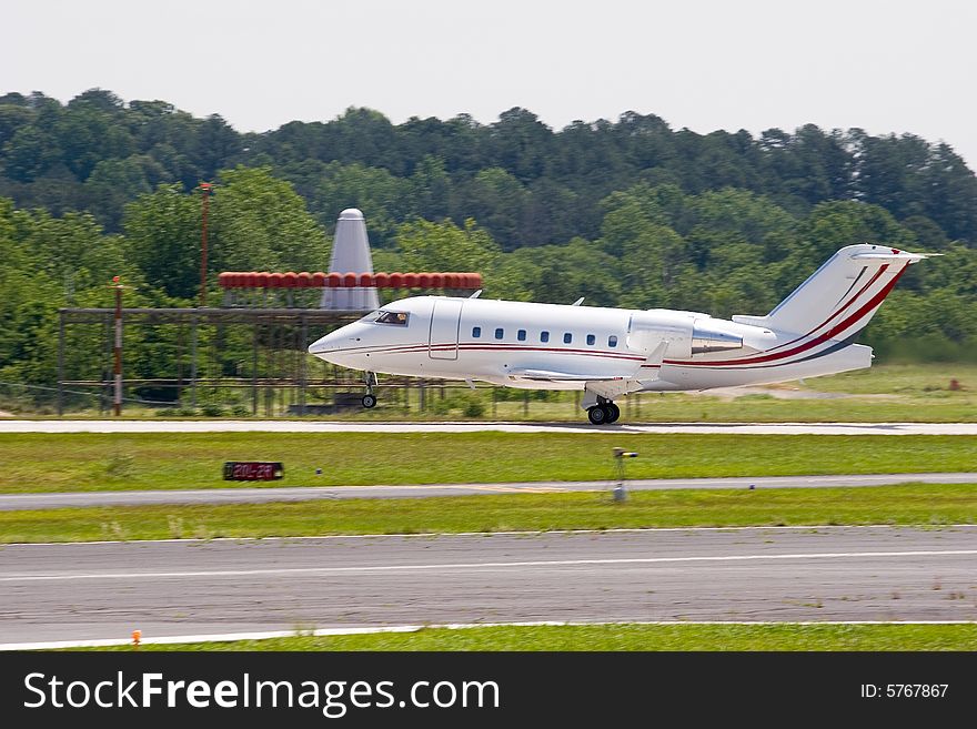 A large private jet touching down on a regional runway. A large private jet touching down on a regional runway