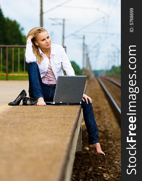 Beautiful young lady with notebook waiting for a train