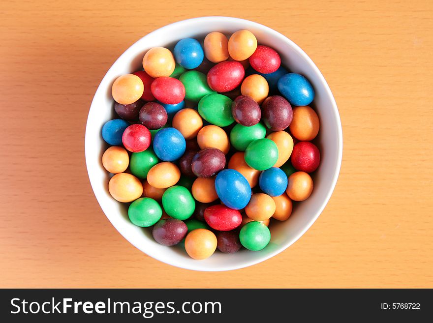 Bowl full of colorful candy on wooden background. Bowl full of colorful candy on wooden background