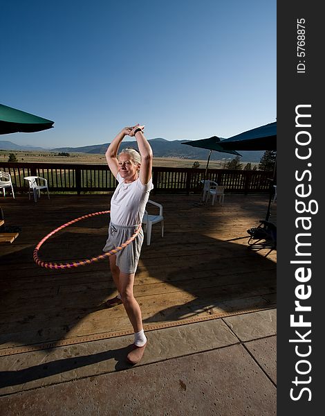 Senior woman hoola hooping on wooden deck with view