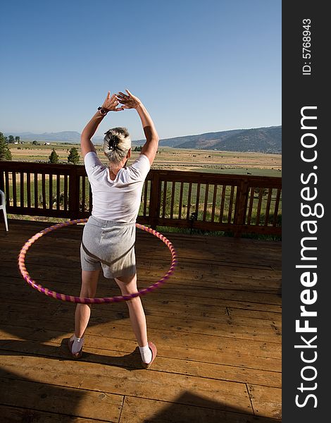 Senior woman hoola hooping on wooden deck with view