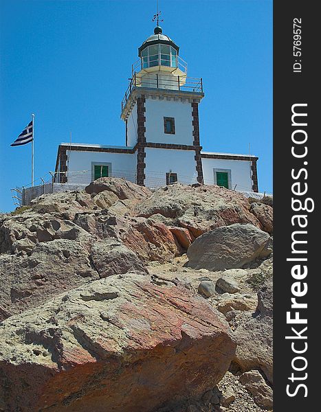 A lighthouse on the rocks on the sunny island of Santorini