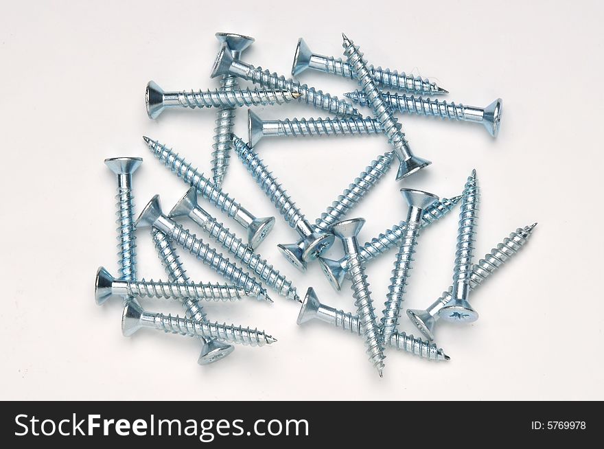 A random pile of screws seen from above and photographed on white background