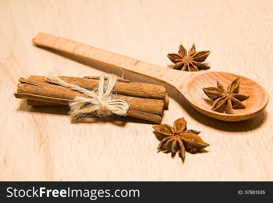 Spoon, cinnamon and star anise on a wooden surface